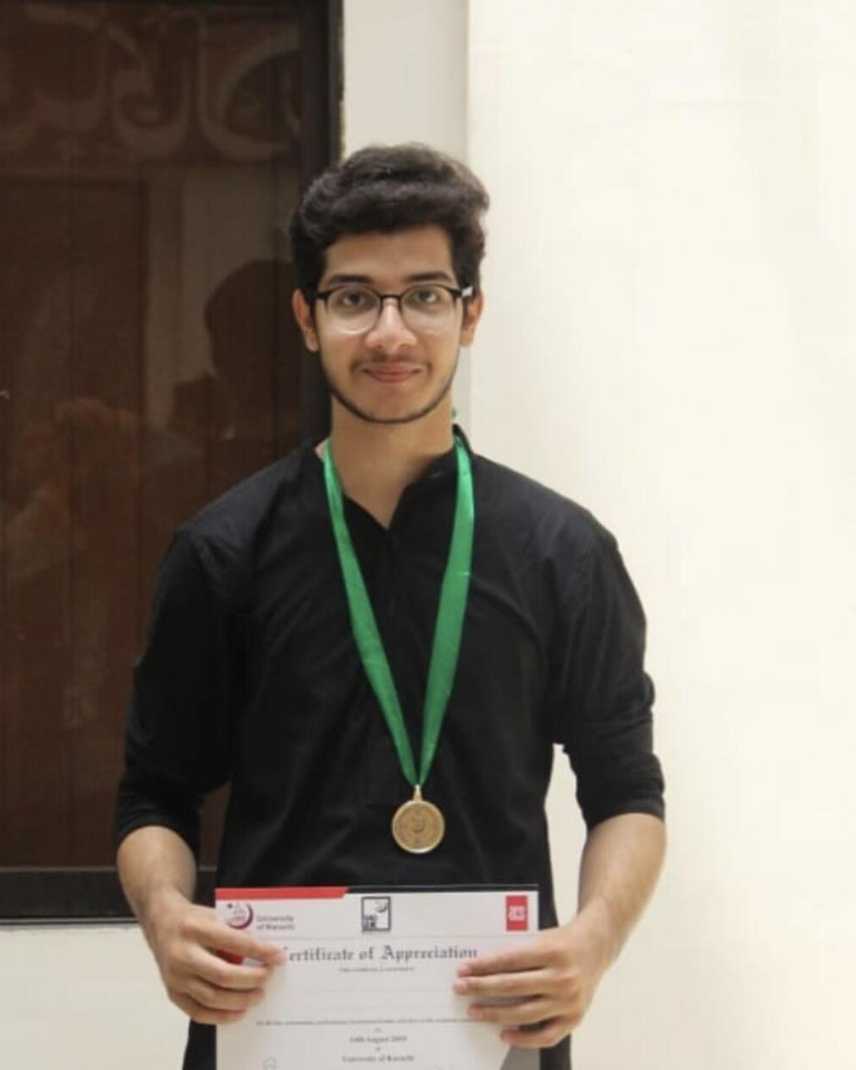 Raza Haider holding his certificate of appreciation and gold medal