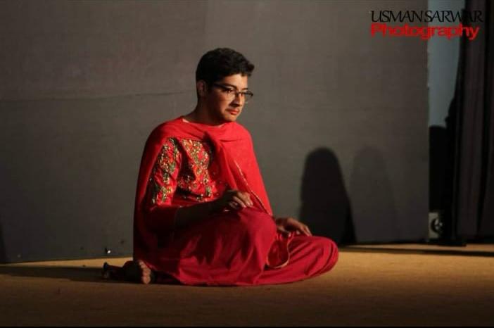 Raza Haider in character on stage, lit in red